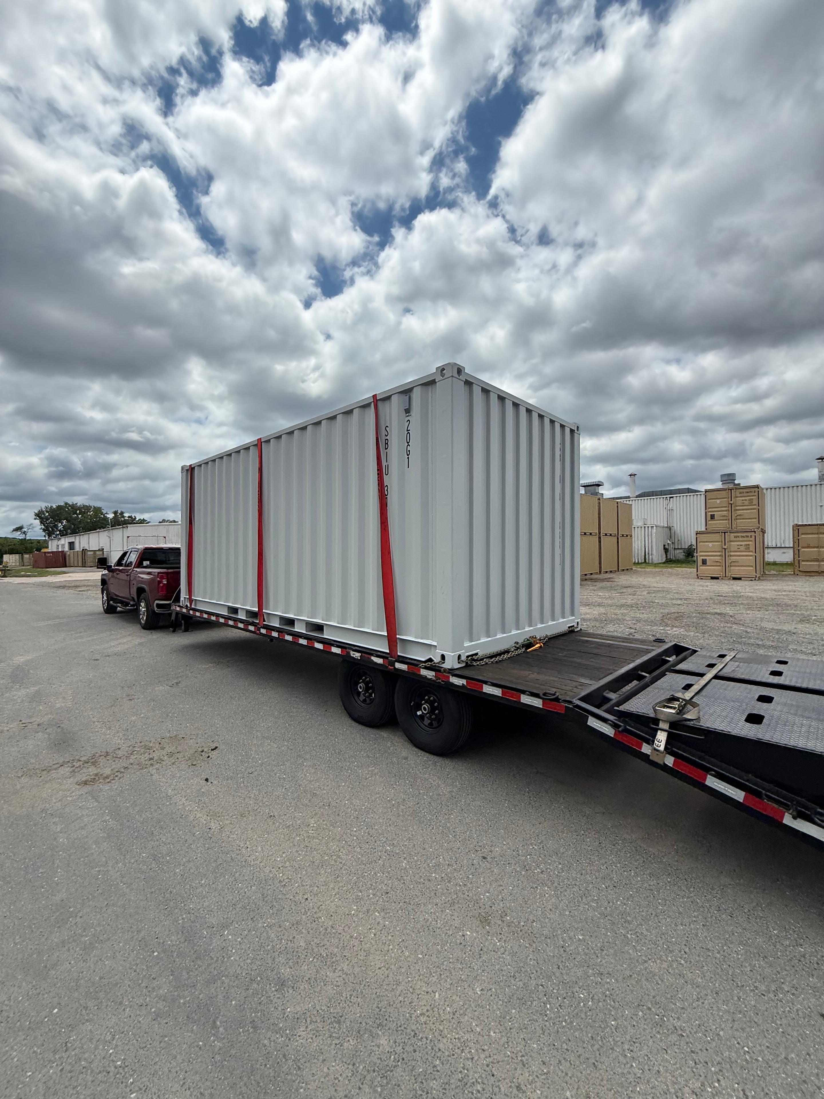 Shipping container secured on flatbed trailer